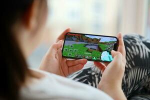 Minecraft mobil ios spel på iphone 15 smartphone skärm i kvinna händer under mobil gameplay foto