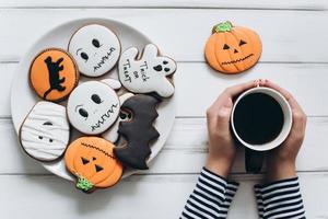 kvinna förbereder sig för halloween, dricker kaffe med pepparkakor foto