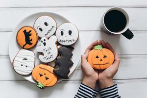 kvinna förbereder sig för halloween och äter läskiga pepparkakor. foto