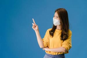 ung asiatisk tjej bär ansiktsmask visar något på tomt utrymme.