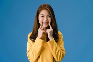 ung asiatisk dam som visar leende, positivt uttryck på blå bakgrund. foto