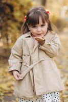 vacker liten flicka visar en luftpuss i höstparken foto
