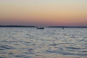 bild av de solnedgång tagen från de strand av de kroatisk kust stad av fazana med en motorbåt foto