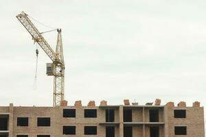 se av en stor konstruktion webbplats med byggnader under konstruktion och flera våningar bostads- hem. torn kranar i verkan på blå himmel bakgrund. hus renovering begrepp foto