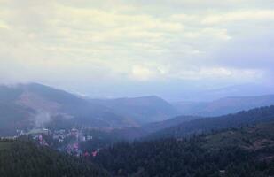 morgon- se av bosatt område och hus runt om de dragobrat berg toppar i karpater berg, ukraina. molnig och dimmig landskap runt om drahobrat toppar foto