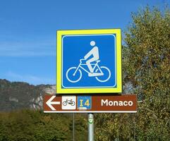 blå cykel väg tecken på trä- posta. grön fält i de bakgrund. Venedig Monaco foto