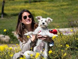 kvinna med vit schnauzer hund i gula blommor fält foto