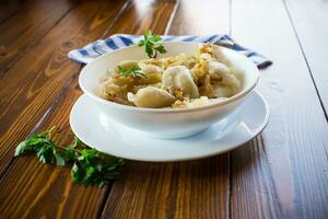 ukrainska vareniky eller pierogi fylld med potatis och svamp, eras med friterad lök. foto