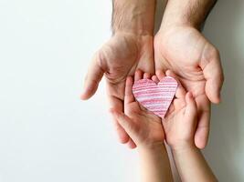 vuxen och barns händer håll små röd papper hjärta. fäder dag. familj, kärlek foto