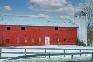 röd ladugård med en vit silo foto