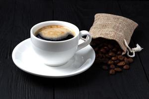 kaffe med skum i en vit kopp och en påse korn foto