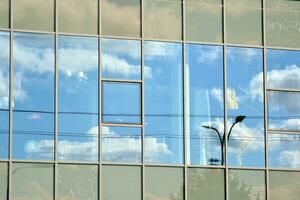 glas byggnad med transparent Fasad av de byggnad och blå himmel. strukturell glas vägg reflekterande blå himmel. abstrakt modern arkitektur fragment. samtida arkitektonisk bakgrund. foto