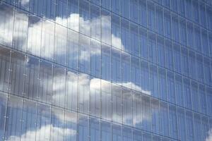 glas byggnad med transparent Fasad av de byggnad och blå himmel. strukturell glas vägg reflekterande blå himmel. abstrakt modern arkitektur fragment. samtida arkitektonisk bakgrund. foto