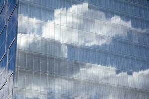 glas byggnad med transparent Fasad av de byggnad och blå himmel. strukturell glas vägg reflekterande blå himmel. abstrakt modern arkitektur fragment. samtida arkitektonisk bakgrund. foto