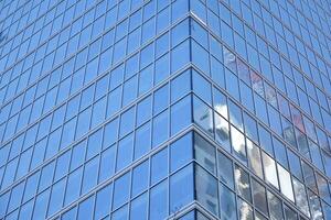 glas byggnad med transparent Fasad av de byggnad och blå himmel. strukturell glas vägg reflekterande blå himmel. abstrakt modern arkitektur fragment. samtida arkitektonisk bakgrund. foto