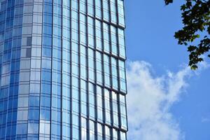 glas byggnad med transparent Fasad av de byggnad och blå himmel. strukturell glas vägg reflekterande blå himmel. abstrakt modern arkitektur fragment. samtida arkitektonisk bakgrund. foto