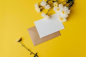 ett tomt kort med kuvert och blomma placeras på gul bakgrund foto