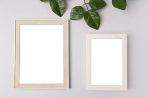 två vita fotoramar och bladgrenar på vit bakgrund foto