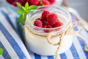 ljuv kokta hemlagad yoghurt med färsk hallon i en glas burk. foto