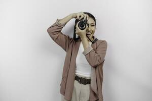 Lycklig leende ung asiatisk kvinna turist stående med kamera tar Foto isolerat på vit studio bakgrund