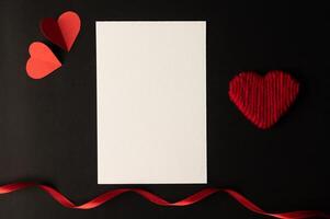 vitt papper och rött hjärtapapper klistrat på en svart bakgrund. foto