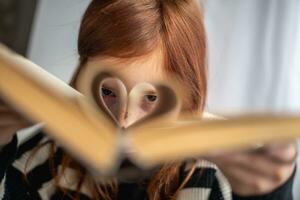 en flicka är innehav en bok. hjärtformade sidor. läsning, menande, inlärning foto