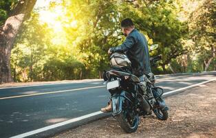 cyklist Sammanträde på hans motorcykel på de sida av de väg. man Sammanträde på hans motorcykel på de sida av de väg foto