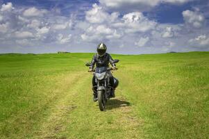 cyklist man på en Land väg, ung man på hans motorcykel reser genom de landsbygden med kopia Plats, man ridning motorcykel i de landsbygden foto