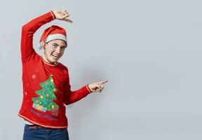 vänlig jul man pekande till en Plats till de sida. vänlig leende ung man i jul kläder pekande på en kampanj, glad jul man begrepp pekande promo erbjudande isolerat foto