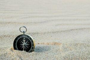 en kompass är Sammanträde i de sand på en strand foto