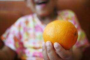 barn innehav en skiva av orange frukt foto