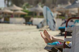 kvinna fötter under liggande i de Sol på en solstol på de strand på semester foto