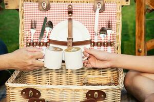 person med en kopp av kaffe med picknick korg i grön trädgård foto