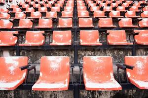 röda tomma och gamla plaststolar på stadion. foto