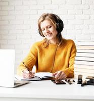 kvinna som studerar online med hjälp av bärbar datorhandstil i anteckningsboken foto