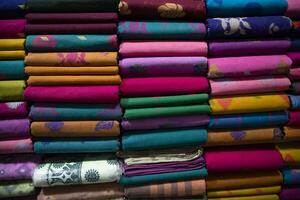 konstnärlig mängd skugga tona färger sarees staplade på detaljhandeln affär hylla till försäljning foto