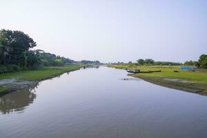 kanal med grön gräs och vegetation reflekterad i de vatten nära padma flod i bangladesh foto
