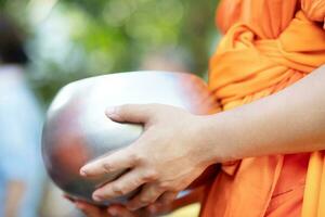 munk med hand som håller ge allmosor skål som kom ut ur erbjudanden på morgonen vid buddhistiska tempel, kulturarv tradition och religion buddhism, sydöstra asien. foto