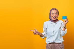 leende asiatisk kvinna som pekar på tomt utrymme och håller tomt kort