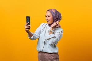 glad asiatisk kvinna tittar på smartphone med upplyft hand foto