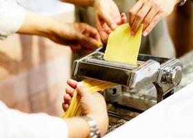 kock som gör pasta med en maskin, hemlagad färsk pasta foto