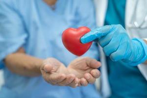 läkare ger rött hjärta till asiatisk senior kvinna patient