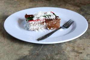 lager tårta och riven kokos på tallrik med bestick, malaysisk mat foto