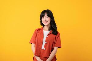 porträtt skön ung asiatisk kvinna söt och blyg klädd i orange kläder isolerat på gul studio bakgrund. foto