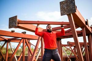 ung man är utövar utomhus. han är håller på med pull-ups. foto