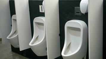 de interiör av de toalett består av en vit keramisk urinoar och tvål maträtt i de hotell med en keramisk golv. rena män toalett foto