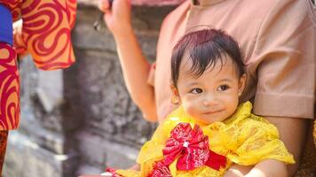liten söt flicka bär gul balinesisk klänning med Fanny uttryck på pappas knä foto