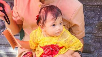 liten söt flicka bär gul balinesisk klänning med Fanny uttryck på pappas knä foto