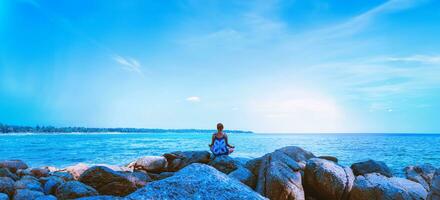 asiatiska kvinnor koppla av i semestern. resa slappna av. spela om yoga. på klipporna vid havet. på sommaren. thailand foto