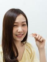 ung asiatisk kvinna som visar hållare efter att ha fått tandställning foto